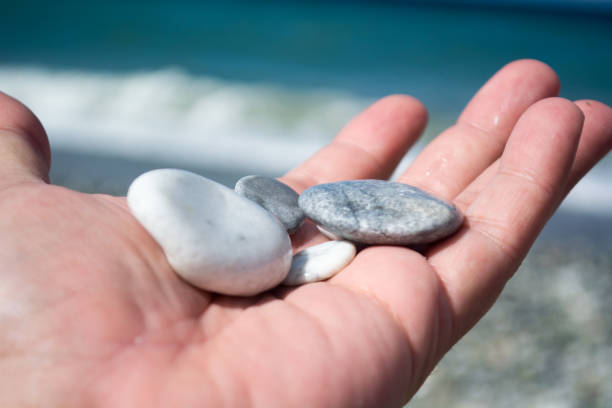 istock Hand with small stones on the beach 936966418