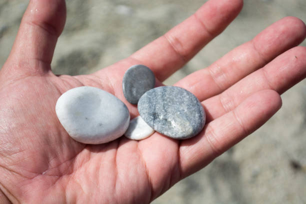 istock Hand with small stones on the beach 936972366