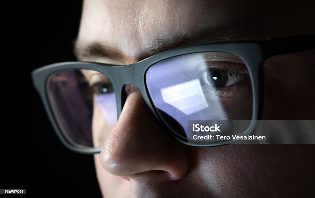 Focused and thoughtful man. Coder, programmer or developer using laptop in dark. Businessman working late. Student studying at night. Focused and thoughtful man. Coder, programmer or developer using laptop in dark. Businessman working late. Student studying at night. Close up of glasses with reflection of computer screen. Eye Stock Photo