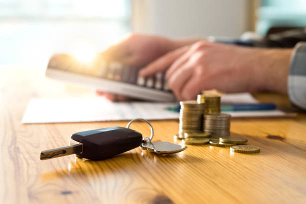 Car keys and money on table with man using calculator. Car keys and money on table with man using calculator. Buyer counting savings and gas cost or salesman calculating sales price, vehicle value or road taxes. service vehicle stock pictures, royalty-free photos & images