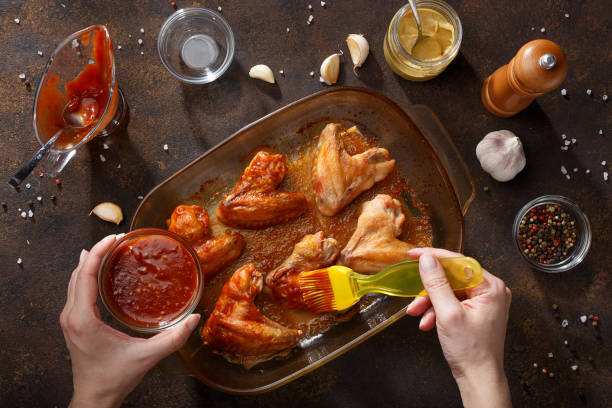 Hands brush baked wings with the bbq souce. stock photo