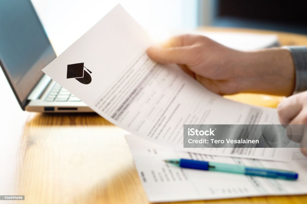 Man reading college or university application or document from school. College acceptance letter or student loan paper. Man reading college or university application or document from school. College acceptance letter or student loan paper. Applicant filling form or planning studies. University Stock Photo