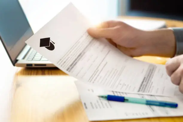 Photo of Man reading college or university application or document from school. College acceptance letter or student loan paper.