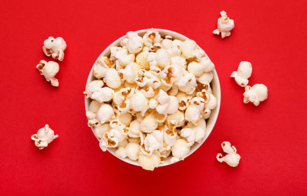 istock Popcorn viewed from above on a red background. Flat lay of pop corn bowl. Top view 936994654