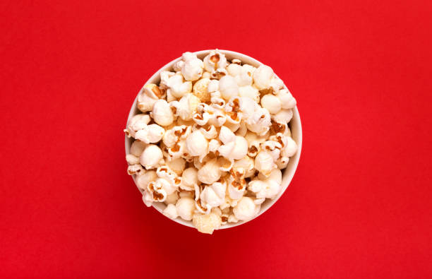 istock Popcorn viewed from above on a red background. Flat lay of pop corn bowl. Top view 936994684