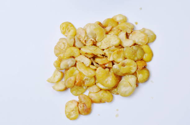 close up of baked salt broad beans on white background