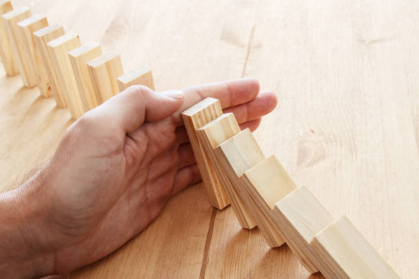 istock a male hand stopping the domino effect. retro style image executive and risk control concept. 937003540