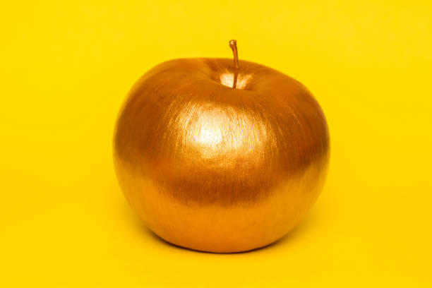 istock Gold apple on yellow background. Creative concept with fruit. 937009526