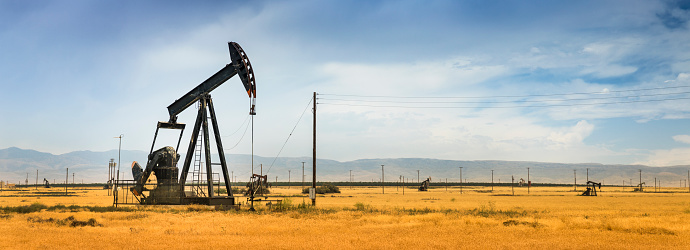 A nodding donkey panorama pumps crude up from the ground on an oil field