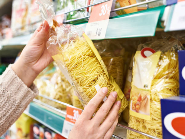 Pack of pasta in hands of buyer at store Pack of pasta in the hands of the buyer at the store grain and cereal products stock pictures, royalty-free photos & images