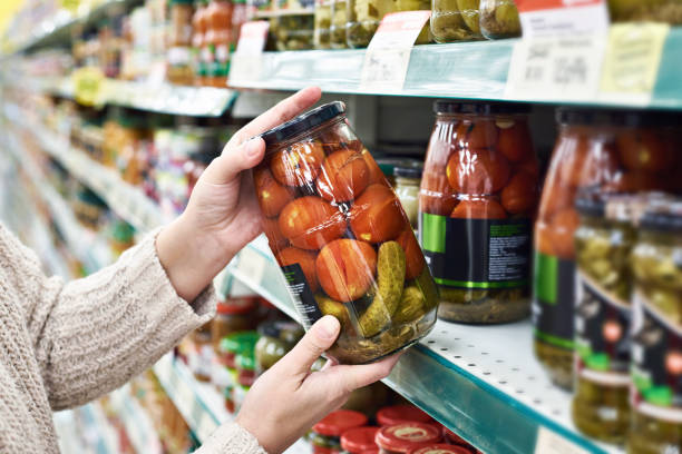 istock Hands with can of salted tomatoes and cucumbers in store 937014016