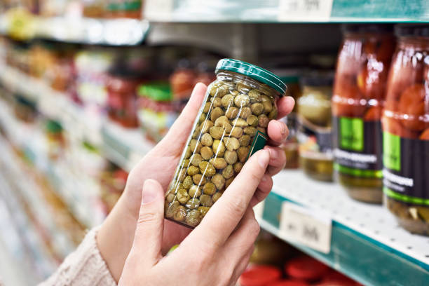 istock Hands with can of canned capers in store 937014100