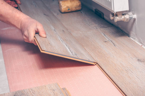 istock The worker's hand with a hammer mounts the floorboard into place 937021414