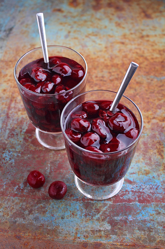 Kissel with cherries in a glass on an old background