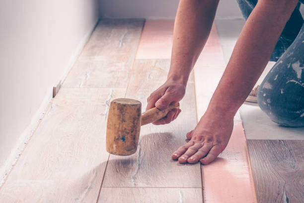 istock The worker's hand with a hammer mounts the floorboard into place 937034682