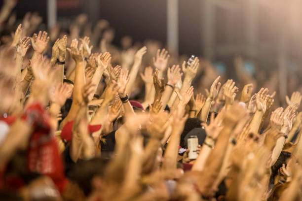 i fan appassionati tifano e alzano la mano a un evento sportivo - cheering foto e immagini stock