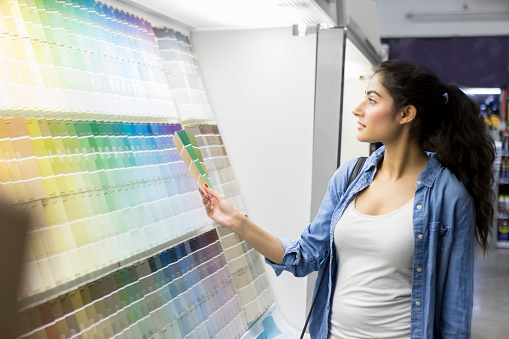 Confident young woman browses paint samples while shopping in home improvement store.