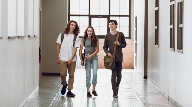 Three students having a discussion and walking the corridor at school Three students having a discussion and walking the corridor at school high school student child little boys junior high stock pictures, royalty-free photos & images