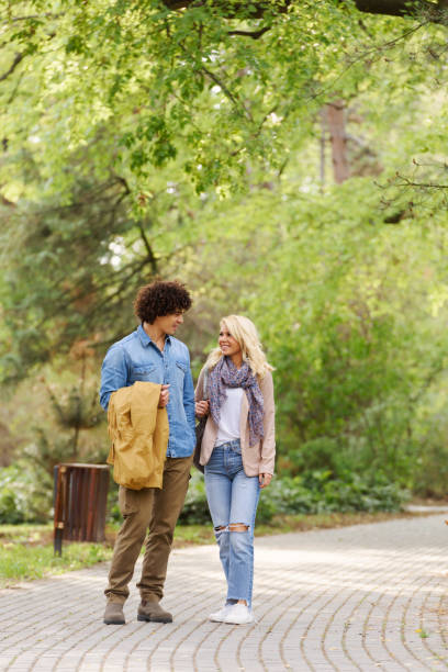 istock Young cheerful couple walking in the park 937049566
