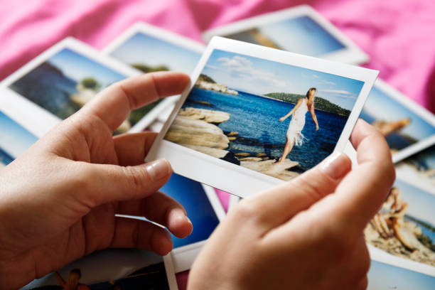 Browsing vacation photographs at home - a closeup Young woman is browsing polaroid images from yesteryear summer vacation she spent with family in Greece. Authentic moments, original photographs. choosing photos stock pictures, royalty-free photos & images