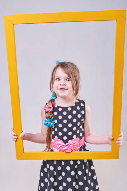 istock Beautiful little girl, with a funny expression on his face, holding a yellow frame 937056796