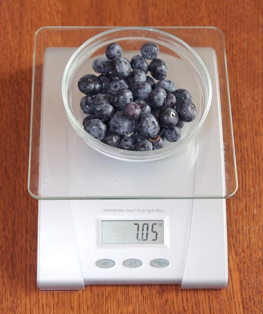 Blue berries in a glass bowl on kitchen scale