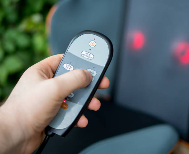 istock Man pressing button on remote control of electric massage seat. 937060978