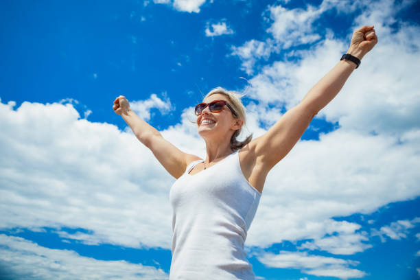 belle femme sans soucis dans le ciel bleu - arms outstretched arms raised women winning photos et images de collection