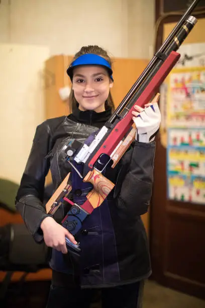 Young beautiful woman smiling and holding a rifle