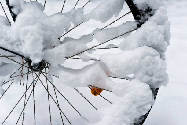 Spoke wheel of a snow covered bicycle parked on a sidewalk in Switzerland.