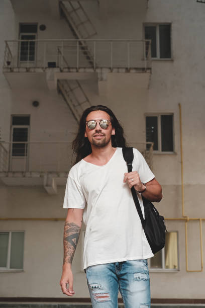 istock Man on urban background with backpack and sunglasses 937075256