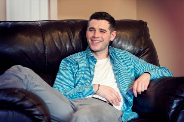 istock Smiling man lounging on his couch 937077486