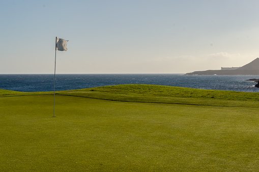 Green golf with flag and hole facing Atlantico ocean in Santa Cruz de Tenerife