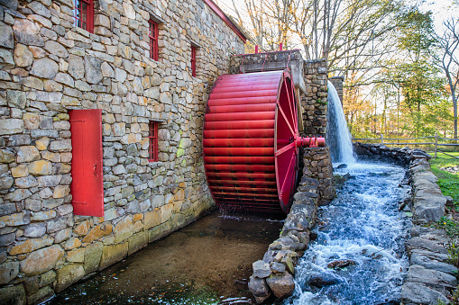 working water mill with a red wheel. Old stone grist mill in Sudbury, MA
