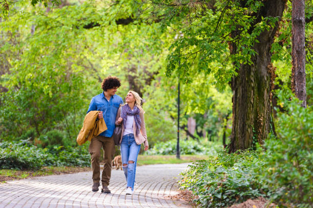 istock Young cheerful couple walking in the park 937096738