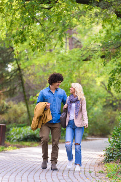 istock Young cheerful couple walking in the park 937097030
