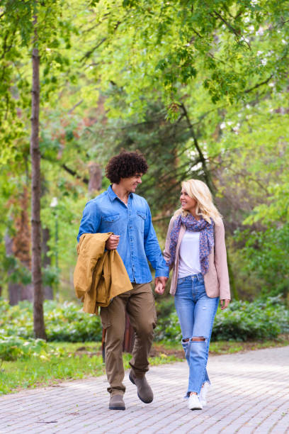 istock Young cheerful couple walking in the park 937099288