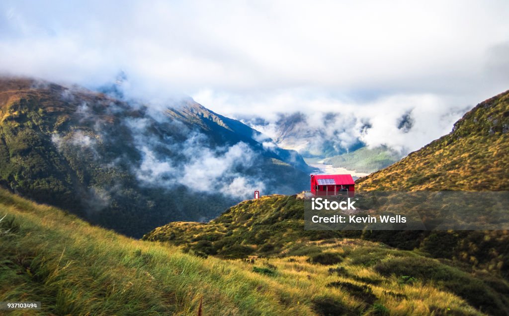 Backcountry Hut on the Edge of a Cliff in New Zealand A backcountry hut sits on the edge of a large cliff in the Matukituki Valley in Mt. Aspiring National Park, New Zealand. Hut Stock Photo