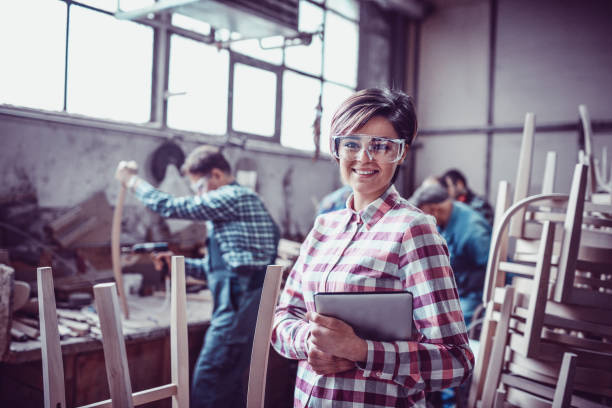 istock Young Smiling Carpenter in Front of Working Team in her Work Shop 937111896