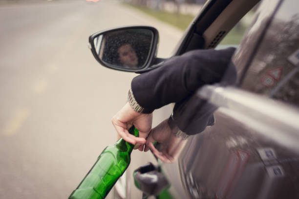 jovem bêbado sentado no carro e segurando a garrafa de cerveja na mão - drunk driving alcohol alcoholism car - fotografias e filmes do acervo