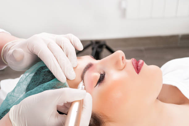 istock Close up of cosmetologist applying permanent make up on female eyebrows 937117314