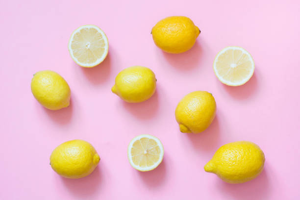 Fresh whole and sliced lemon on pink background. Flat lay.