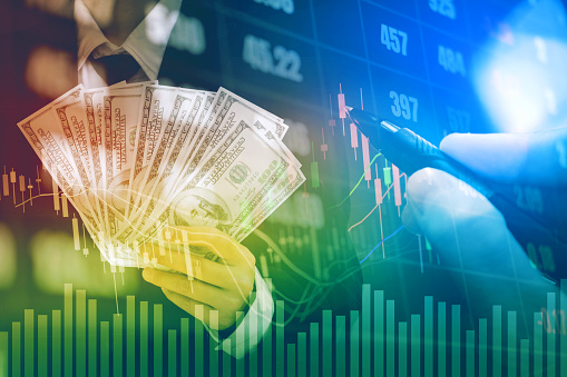 Businessman Holding money US dollar bills on digital stock market financial exchange information and Trading graph background