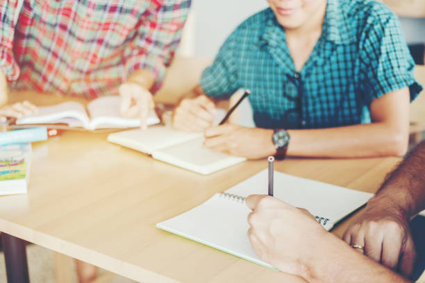 istock High school or college students studying and reading together in library 937138470