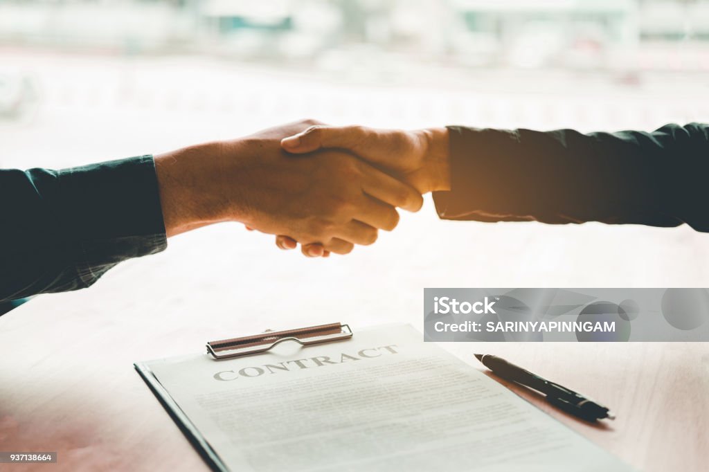 Empresarios negociando un apretón de manos de contrato entre dos colegas - Foto de stock de Contrato libre de derechos