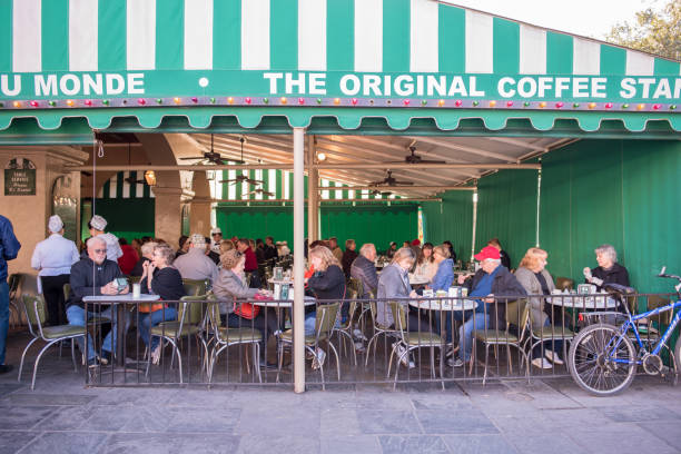 People eating at Cafe du Monde in the French Quarter New Orleans, LA, January 25, 2018: People enjoying a breakfast of coffee and beignets at the famous and iconic Cafe Du Monde, in the French Quarter. As many as ten million people visit the city yearly beignet stock pictures, royalty-free photos & images