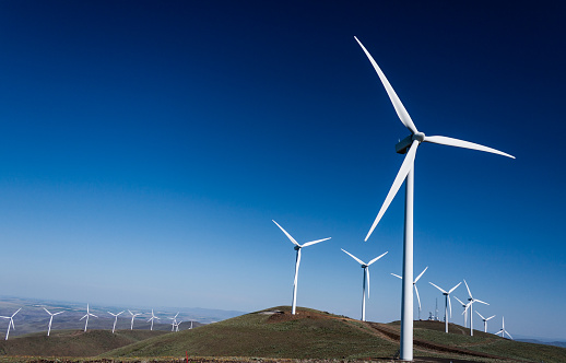 Power turbine wind mills on rolling hills with a blue sky