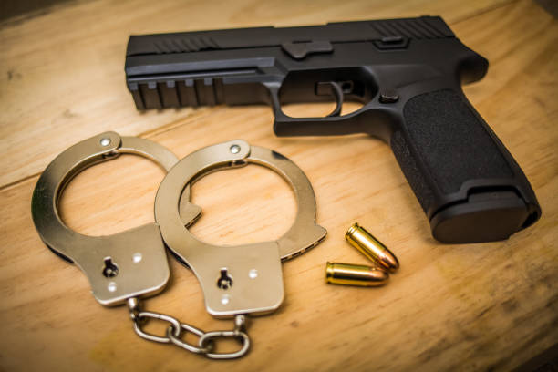 istock Hand gun with hand cuffs on wooden surface 937150724