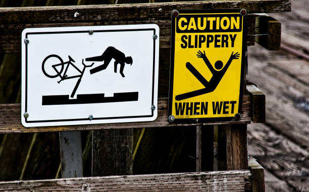 Bicycle and slip & fall danger signs on a wooden rail