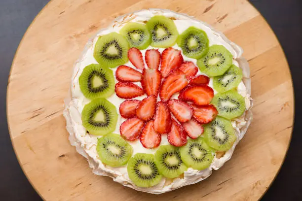 Photo of Pavlova Cake Traditional Iconic Australian Dessert. Homemade Meringue Pie Decorated with Fresh Fruit Strawberry and Kiwi